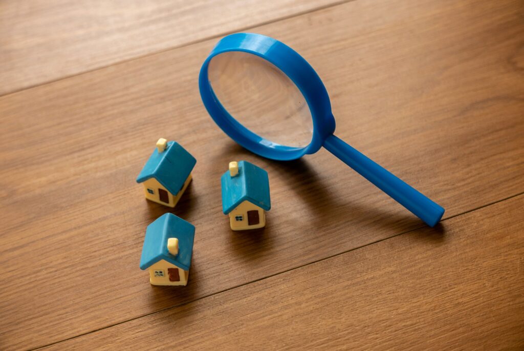 Concept of house search, land and property valuation. Magnifying glass and house model.