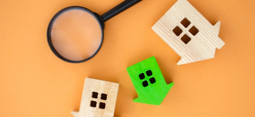 Magnifying glass and wooden houses. House searching concept. Home appraisal.